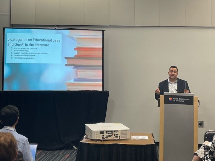Daher presenting a slide about educational uses of AI to an audience in a conference room.