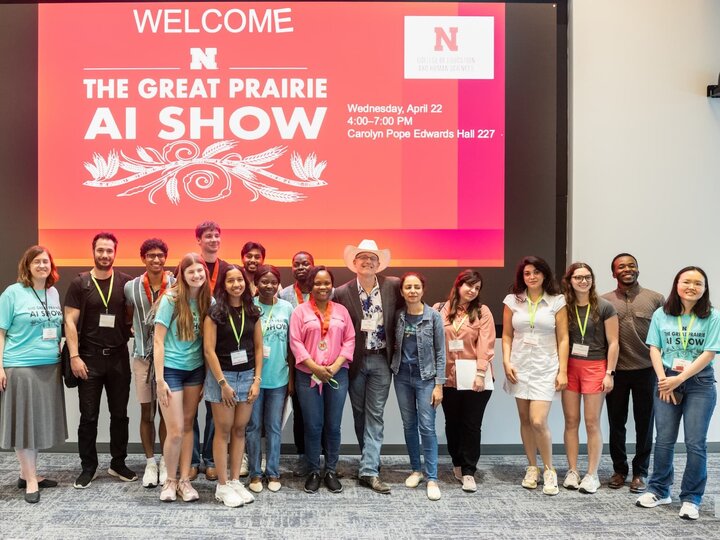 Group of people smiling in front of a red screen displaying "The Great Prairie AI Show."